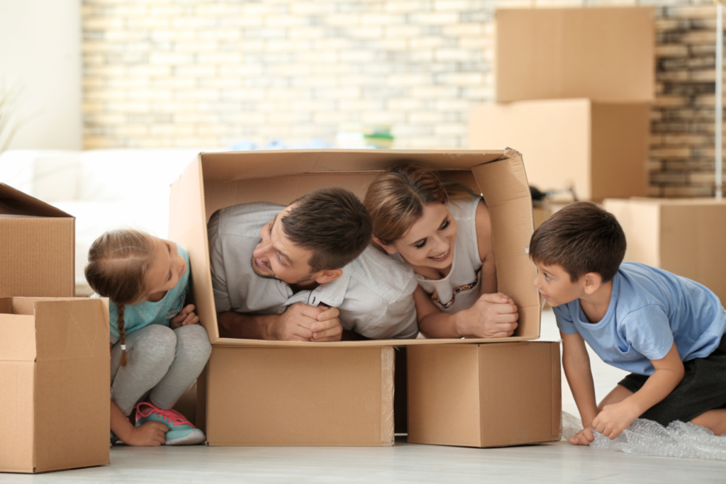 Eine glückliche Familie spielt mit Umzugskartons in ihrem neuen Zuhause – ermöglicht durch eine reibungslose Vermietung und Betreuung durch die Hausverwaltung.