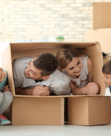 Eine glückliche Familie spielt mit Umzugskartons in ihrem neuen Zuhause – ermöglicht durch eine reibungslose Vermietung und Betreuung durch die Hausverwaltung.