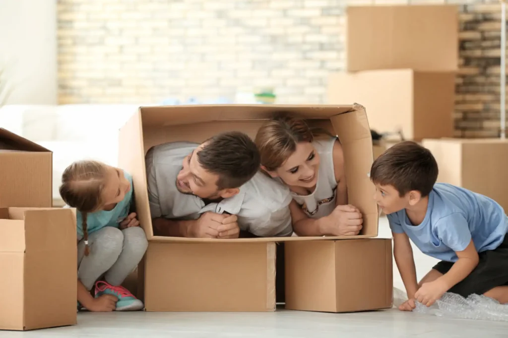 Eine glückliche Familie spielt mit Umzugskartons in ihrem neuen Zuhause – ermöglicht durch eine reibungslose Vermietung und Betreuung durch die Hausverwaltung.
